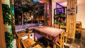 Een gezellig restaurant met een houten inrichting, een tafel met een strepen tafelkleed en uitzicht op de straat.