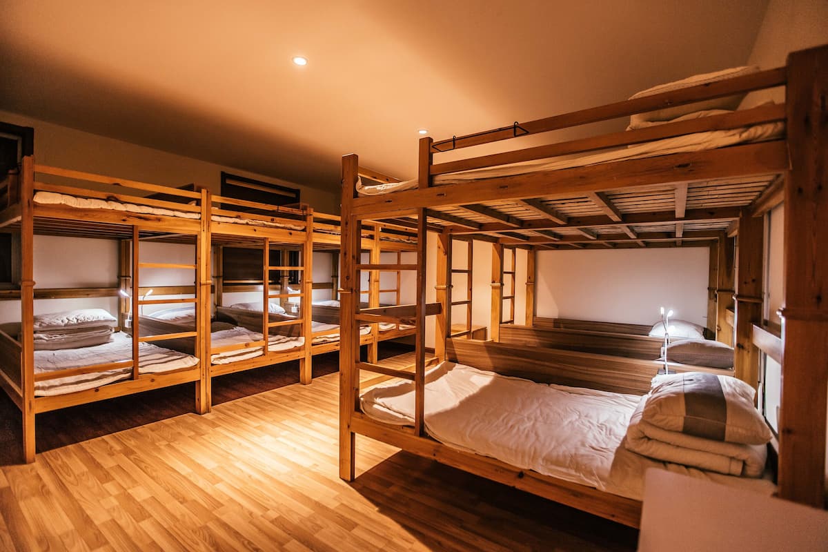 Een slaapzaal met stapelbedden, houten vloeren en een eenvoudig, praktisch ontwerp.