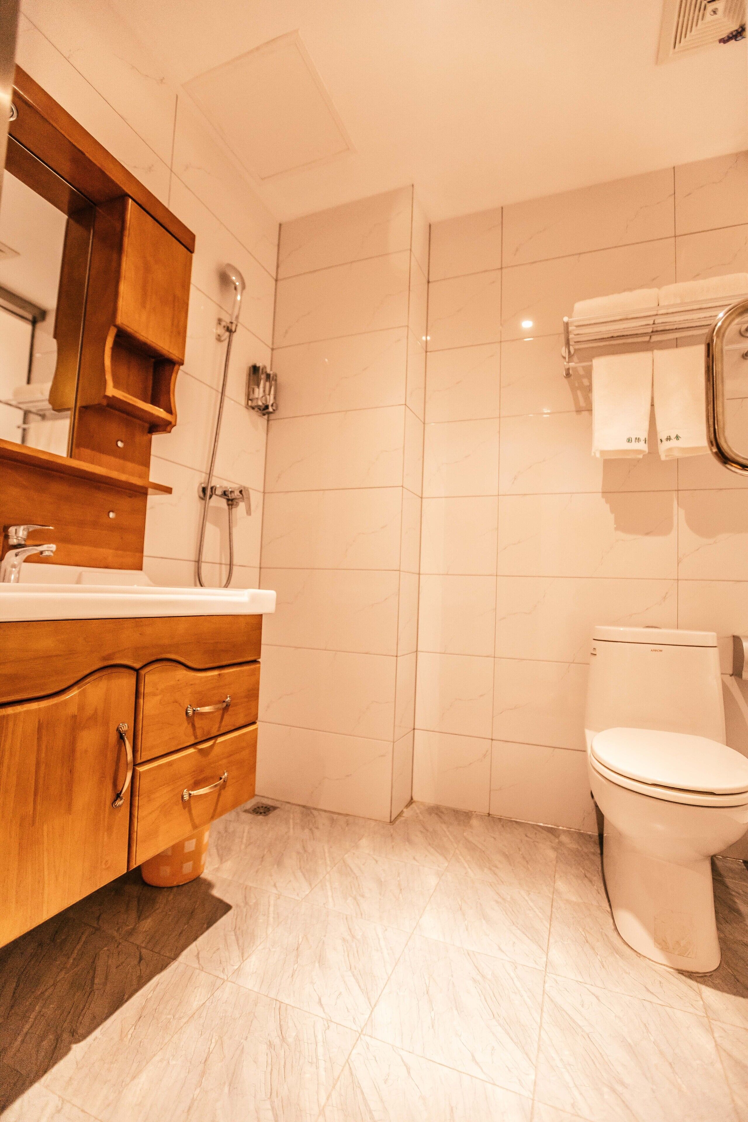 Un baño con tocador de madera, lavamanos blanco, inodoro y ducha.