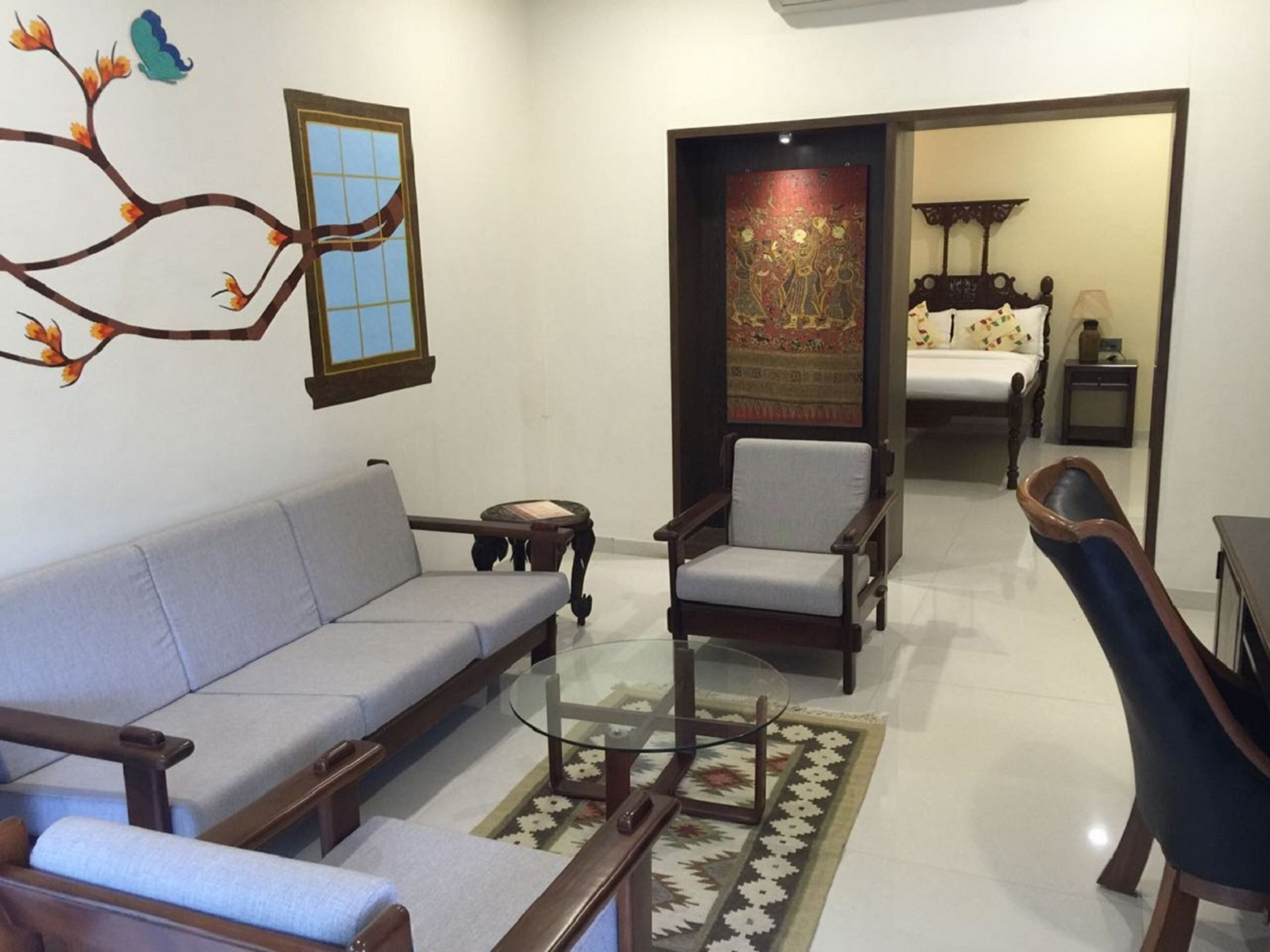 A living room with a sofa, armchairs, a glass coffee table, and a decorative rug.