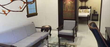 A living room with a sofa, armchairs, a glass coffee table, and a decorative rug.