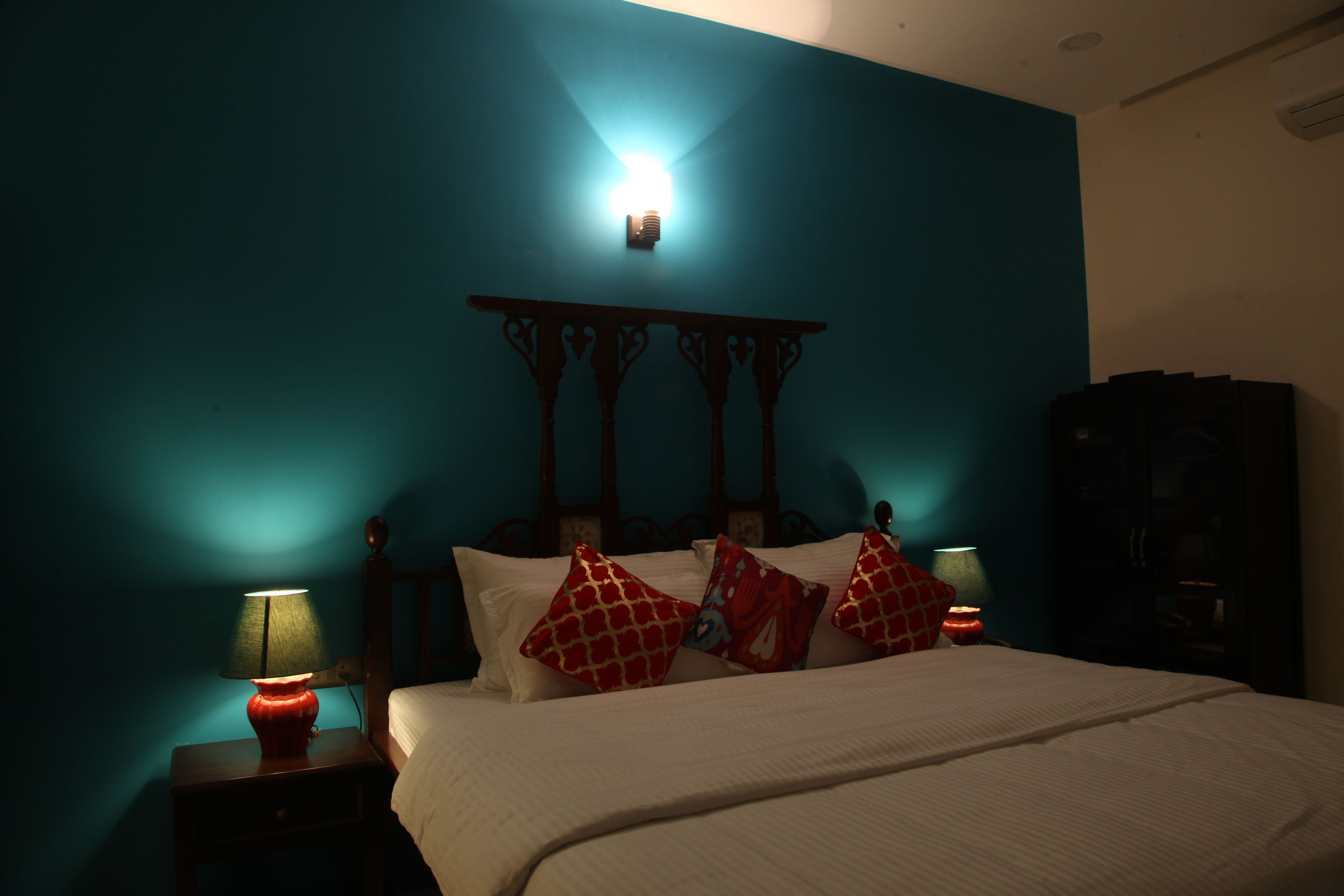 Un dormitorio con cama, mesitas de noche, luz empotrada en la pared y cabecero.