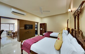 Een hotelkamer met twee bedden, een televisie, een airconditioner en een plafondventilator.