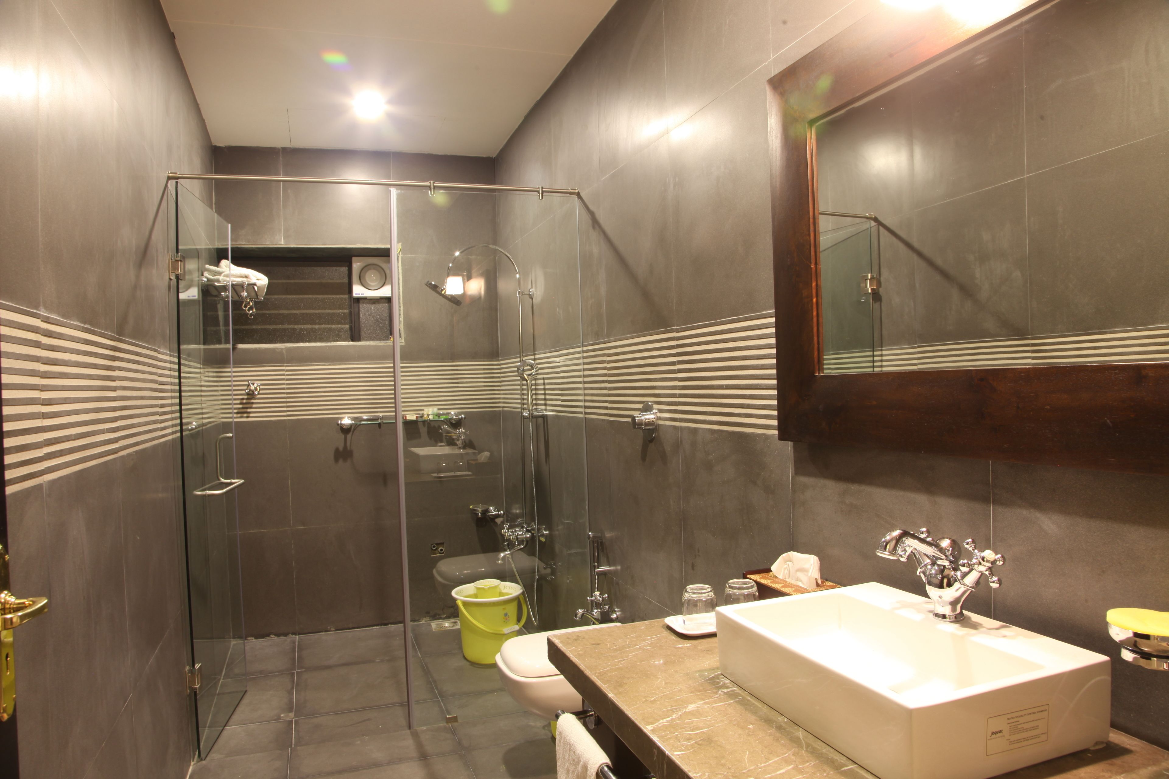 Un baño moderno con ducha envuelta en vidrio, un lavamanos blanco y un espejo grande.