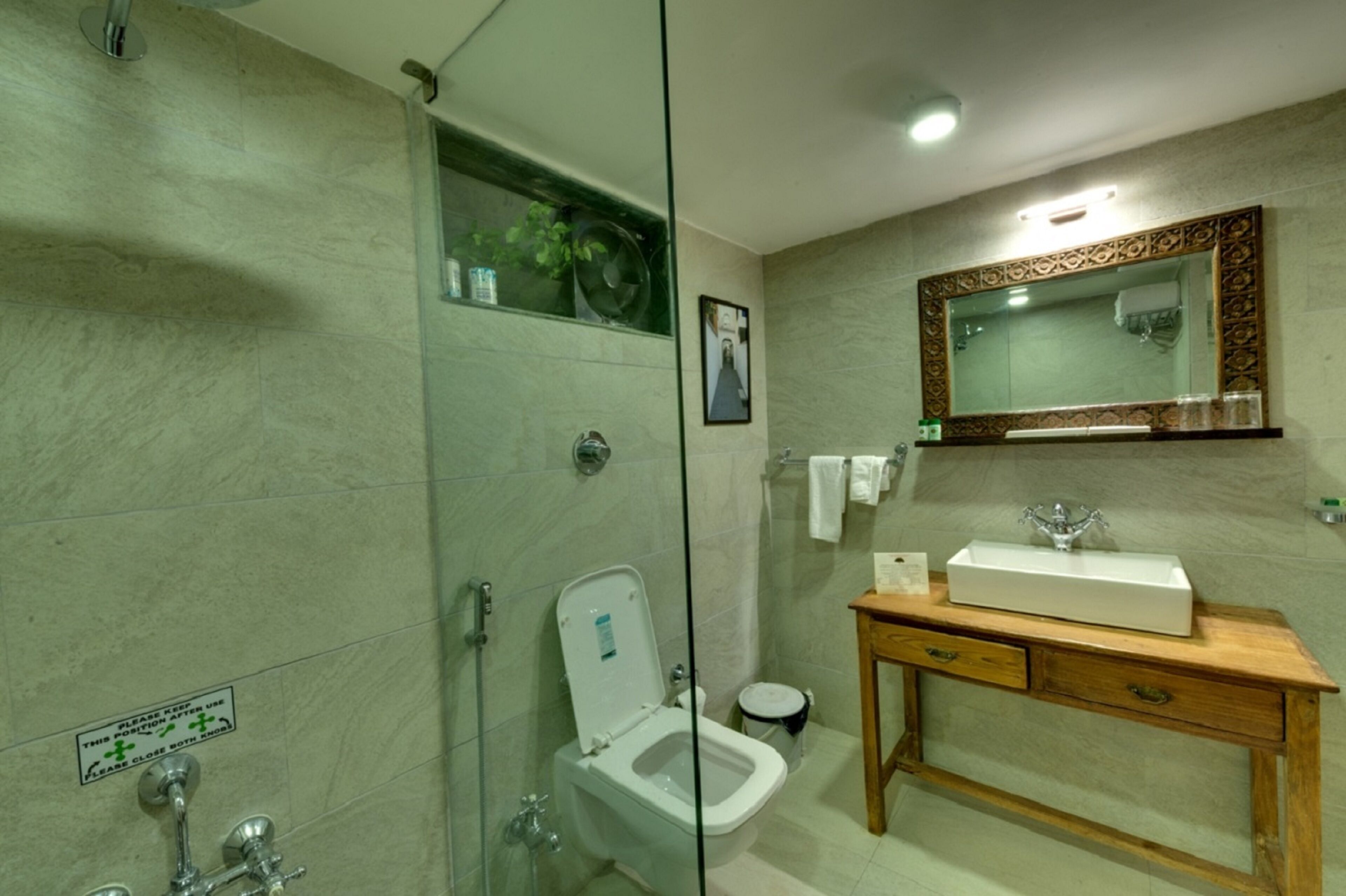 Een badkamer met een douche met glazen wand, een wit toilet, een houten wastafelmeubel met een spiegel en een wastafel.