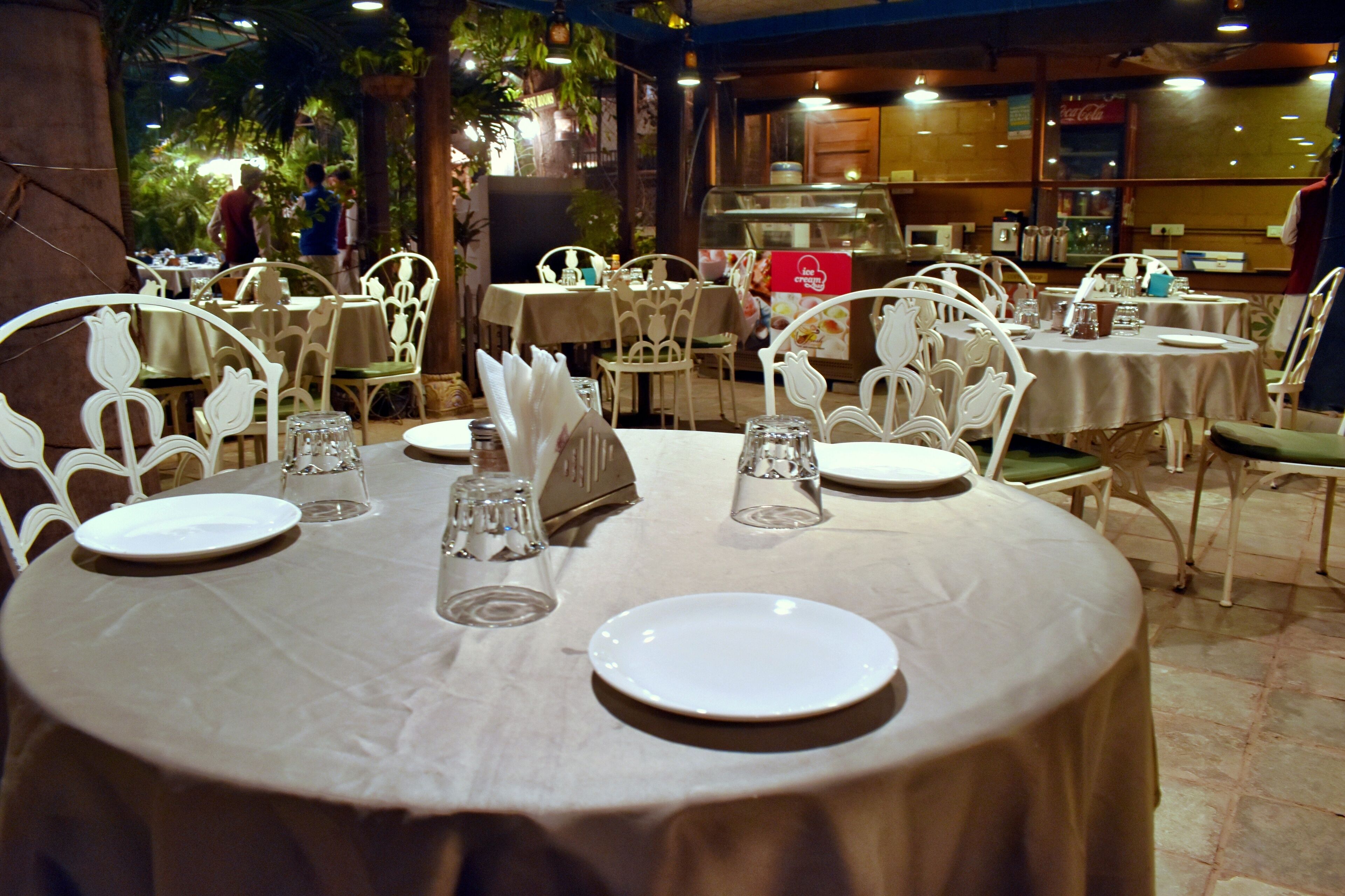 Ein Restaurant mit runden Tischen, gedeckt mit weißen Tellern, Gläsern und Besteck.