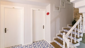Una escalera con peldaños de madera y balaustres blancos, que conduce a un rellano con piso estampado.