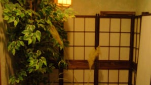 A traditional Japanese room with tatami flooring, a shoji screen, a hanging lantern, and a small bonsai tree. - Hotel Senke (Myoko)