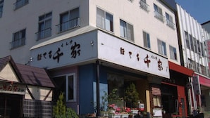 A multi-story building with commercial spaces on the ground floor. - Hotel Senke (Myoko)