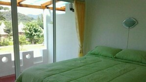 A room with a bed, a window, and a view of greenery outside. - Ban Rai Pornsawan (Suan Phueng)
