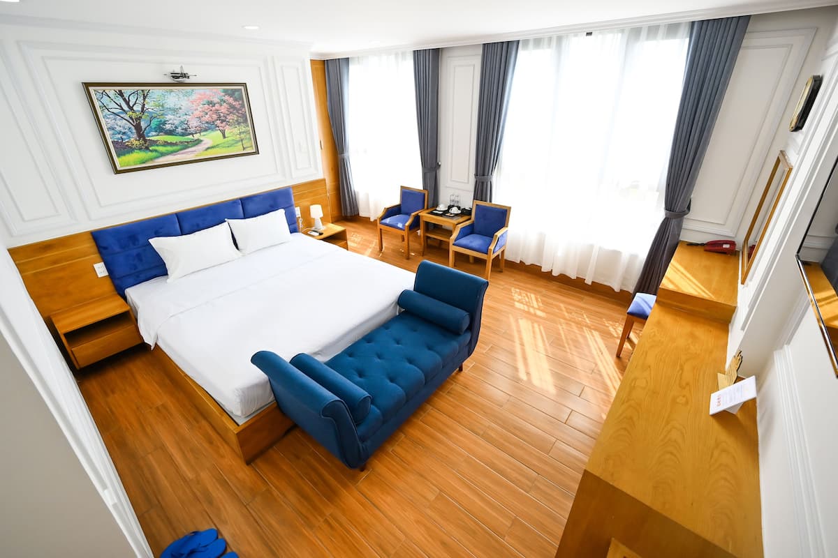 Une chambre d’hôtel avec un grand lit, un bureau, deux chaises et un tableau au mur.