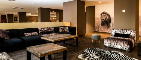Et moderne loungeområde med sofasæt, sofabord og en fodsækkestol med zebraprint.