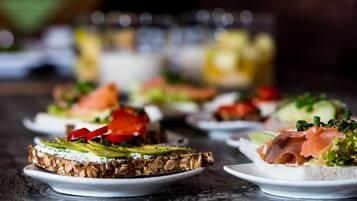 A variety of appetizers on white plates, including items with smoked salmon, avocado, and vegetables, on a wooden table.