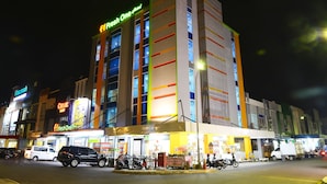 Un hôtel à plusieurs étages, doté d’une enseigne lumineuse, notamment les noms « Fresh One Hotel » et « Chloe’s ».