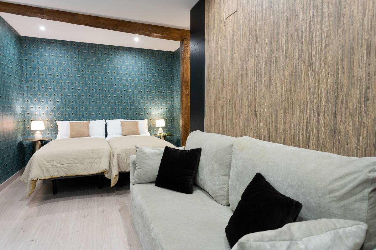 A hotel room with two beds, a sofa, and a wooden accent wall.