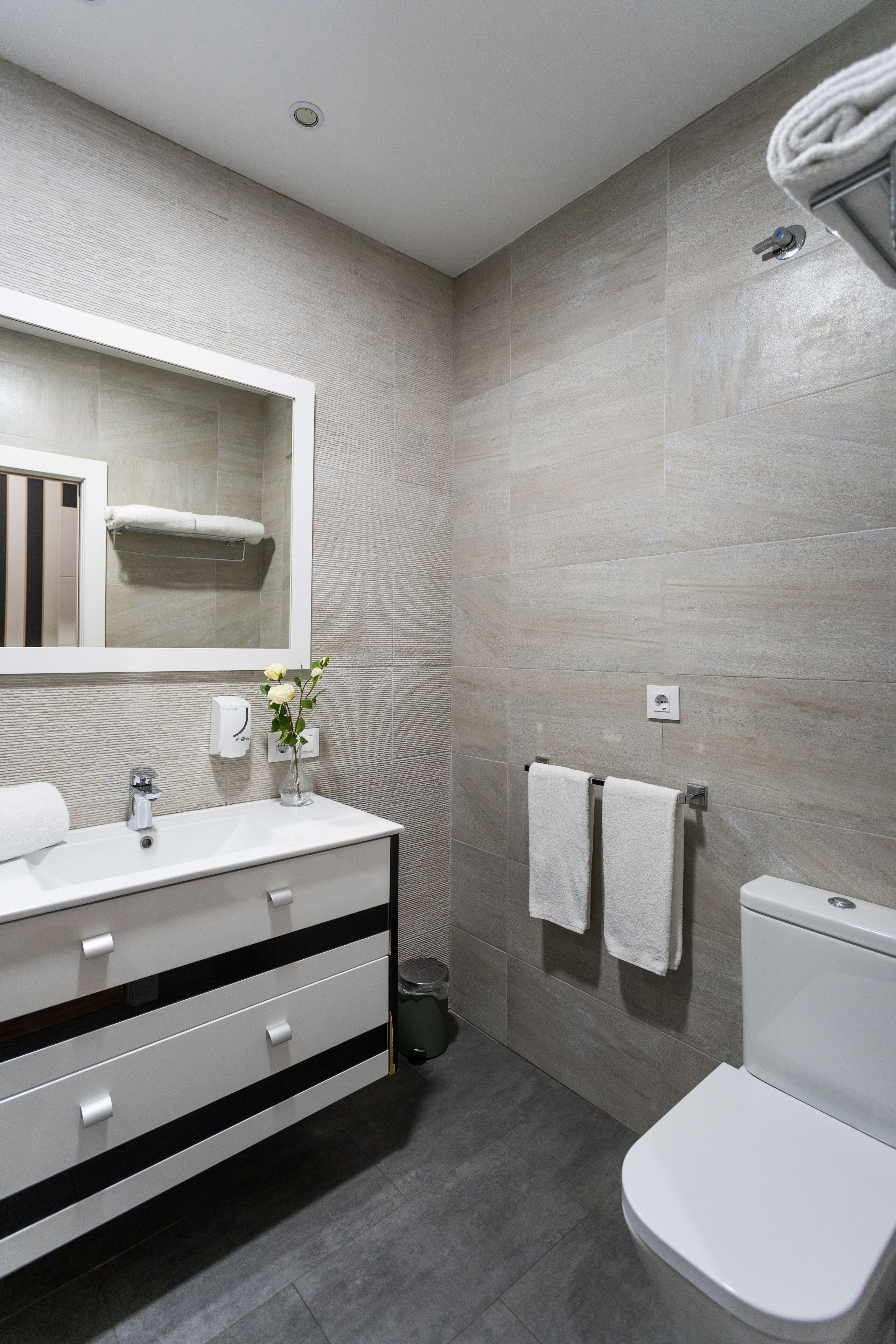 Un baño moderno con un lavamanos, espejo y retrete blancos.