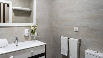 Un baño moderno con un lavamanos, espejo y retrete blancos.