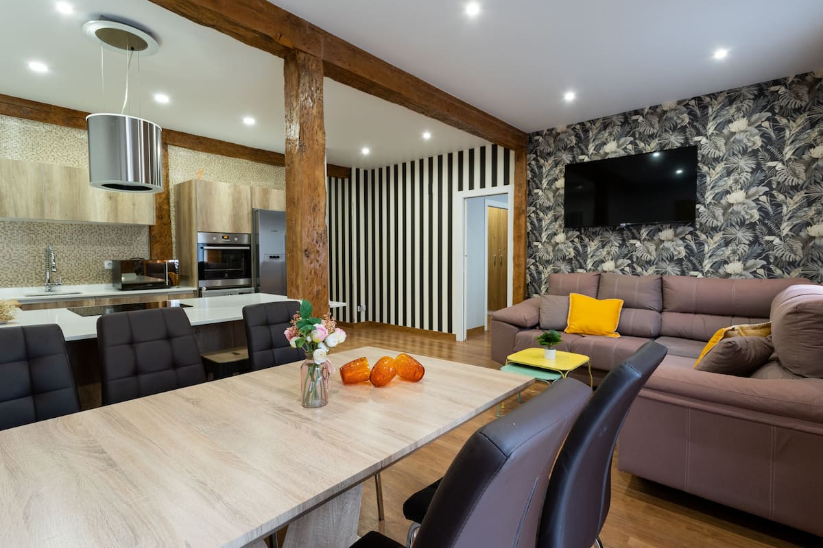A modern living room with a sofa and a dining area with a table and chairs.
