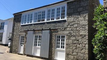 A two-story stone building with large windows and a white door.