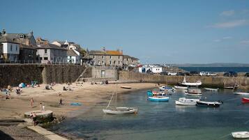 A coastal town with a stone wall, beach, and boats.