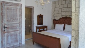 Ein Schlafzimmer mit einem hölzernen Bett, einer Kristallleuchter, einem Spiegel und einer Steinwand.