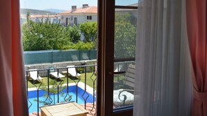 Ein Balkon mit Pool, Blick auf ein Gebäude und viel Grün.