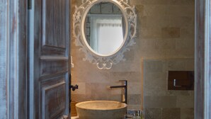Ein Badezimmer mit rundem Spiegel, einem Steinsinkenschrank und einer Toilette.