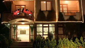 A multi-story hotel with balconies, a neon sign, and a well-lit entrance. - Prestij Apart Hotel (Akcakoca)