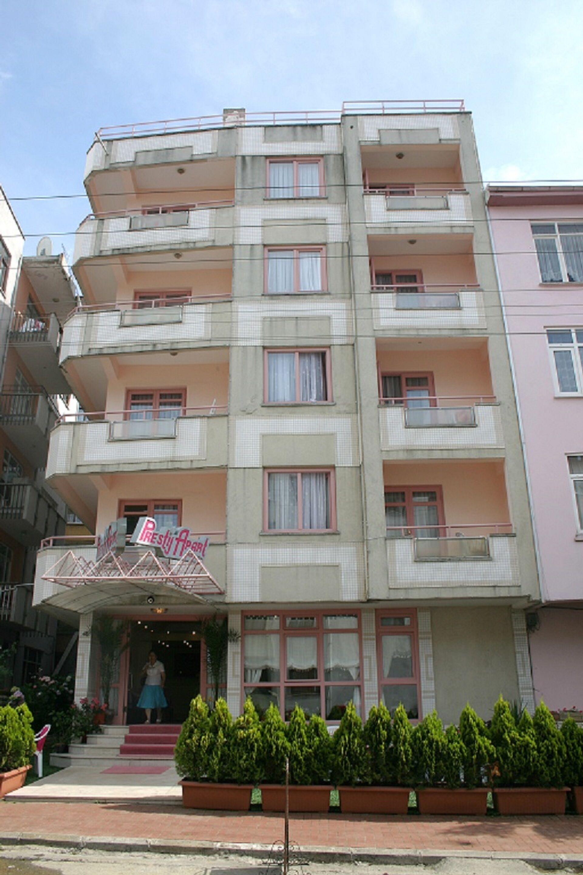 A multi-story hotel with balconies, a central entrance, and a signboard.