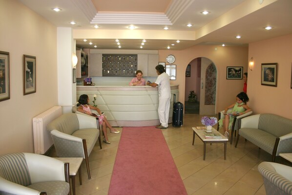 A hotel lobby with a reception desk, seating area, and a clock on the wall. - Prestij Apart Hotel (Akcakoca)