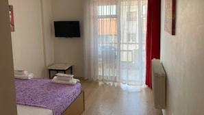 A bedroom with a bed, a TV mounted on the wall, a small table, and a window with curtains. - Prestij Apart Hotel (Akcakoca)