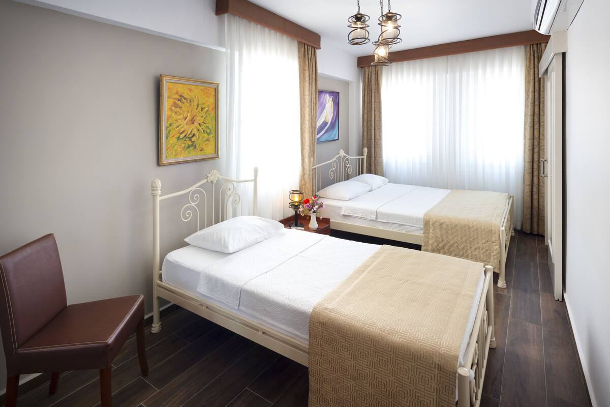 A hotel room with two beds, a chair, and artwork on the walls.
