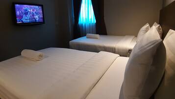 A hotel room with two beds, a TV on the wall, and a window with curtains.