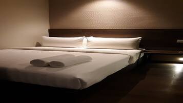 Una habitación de hotel con una cama bien hecha, un cabecero de madera y una mesita de noche pequeña.