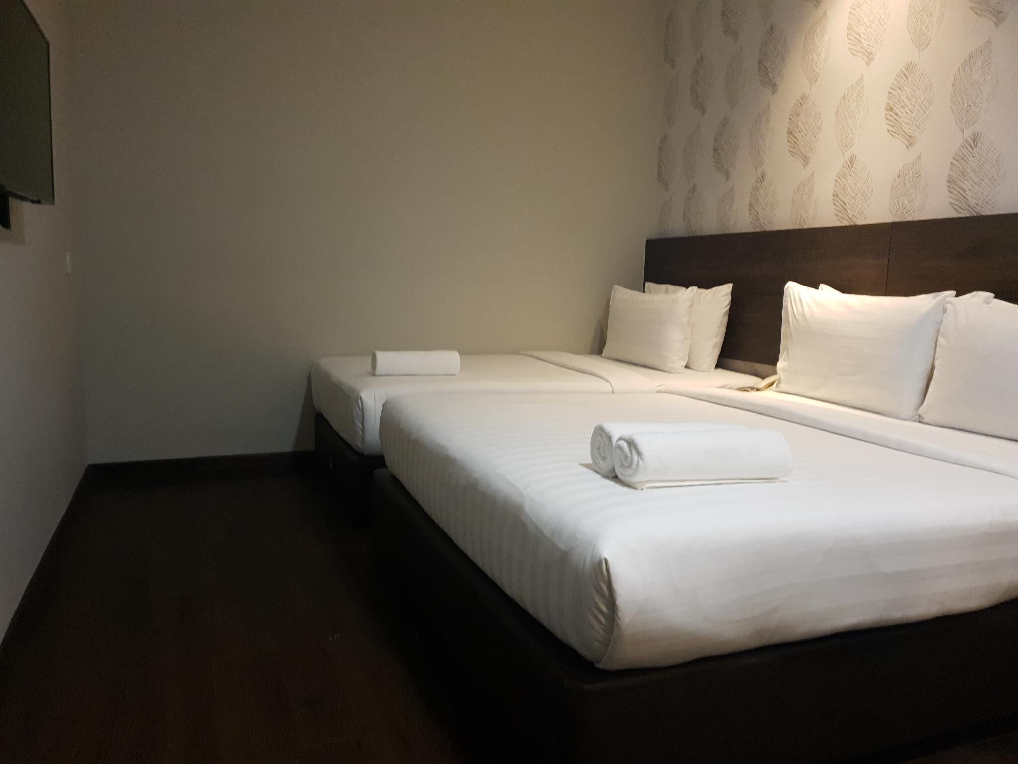 Een hotelkamer met een groot bed, een nachtkastje en een muur met een bladmotief.