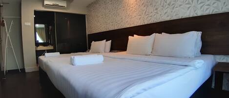 A hotel room with two beds, a wardrobe, a mirror, and a patterned wall.