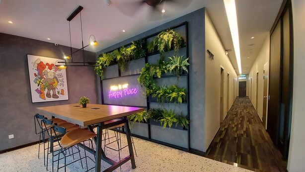 Um interior moderno com uma mesa e cadeiras de madeira, um letreiro de neon e um arranjo de plantas na parede.