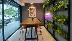 Um interior moderno com mesa de jantar de madeira, ventoinha no teto e parede com jardins verticais.