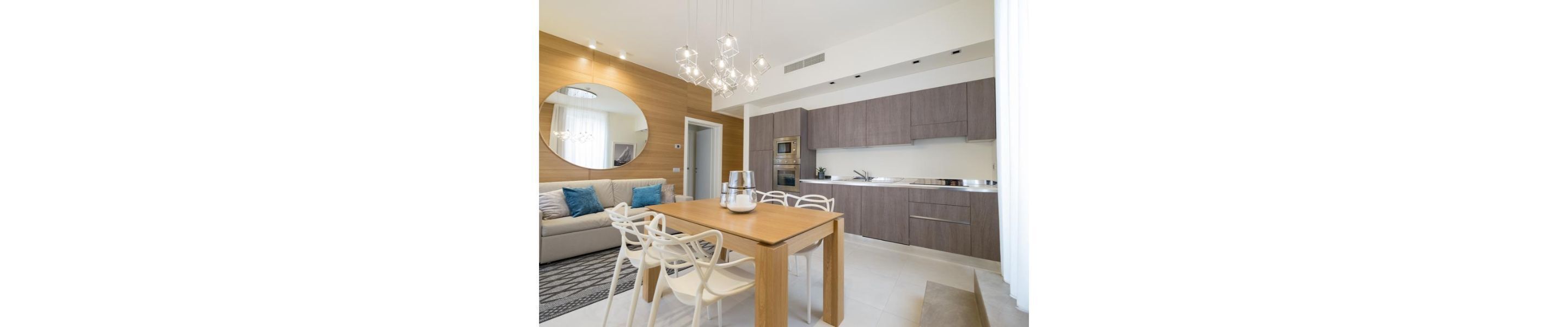 A modern kitchen with grey cabinets, a wooden dining table, and white chairs.