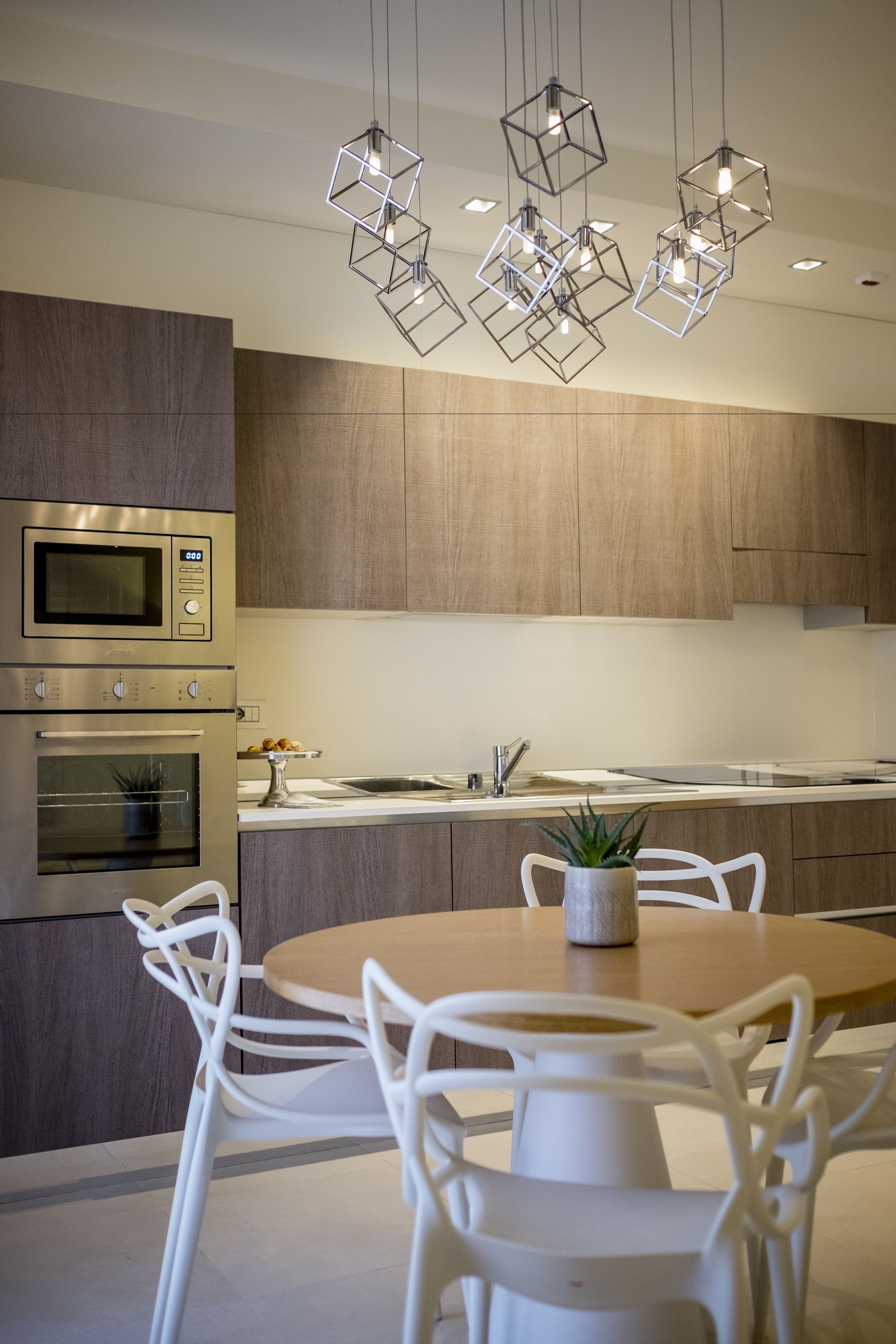 A modern kitchen with stainless steel appliances, a wooden dining table, and white chairs.