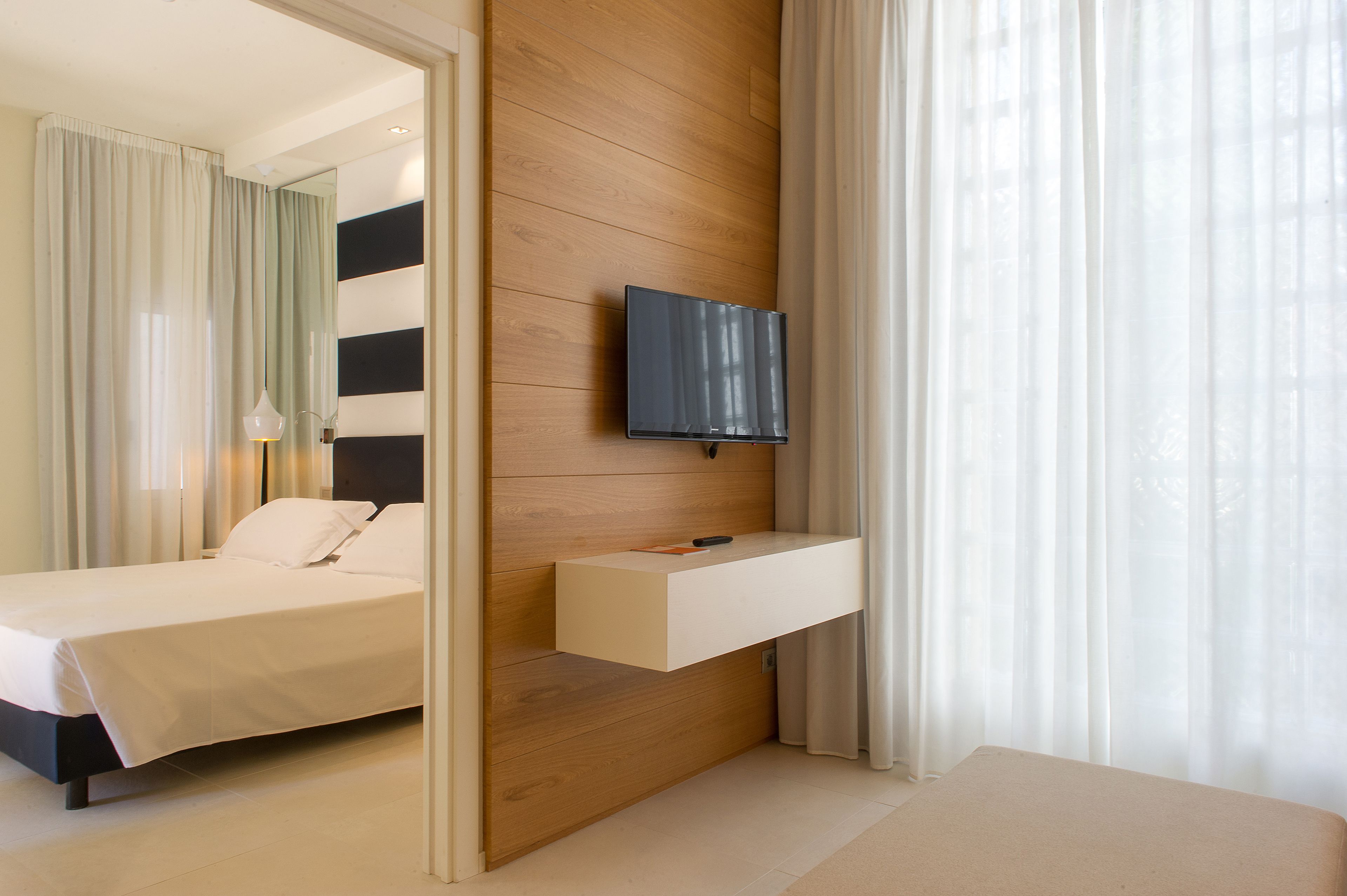 Une chambre d’hôtel moderne équipée d’un lit, d’un téléviseur fixé au mur et d’une étagère intégrée.