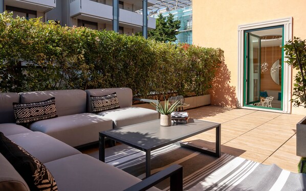 A modern outdoor seating area with a sofa, a coffee table, and a potted plant. - Metropol Ceccarini Suite - Luxury apartments (Riccione)