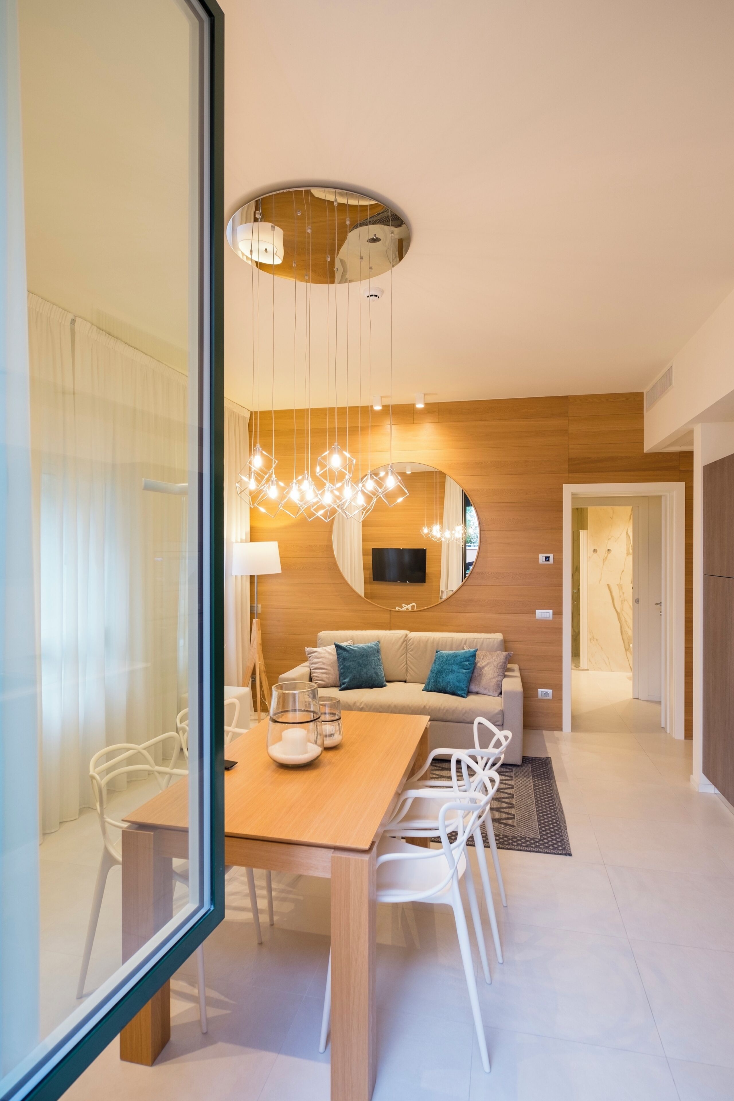 Un comedor moderno con una mesa de madera, sillas blancas y una lámpara de techo original.