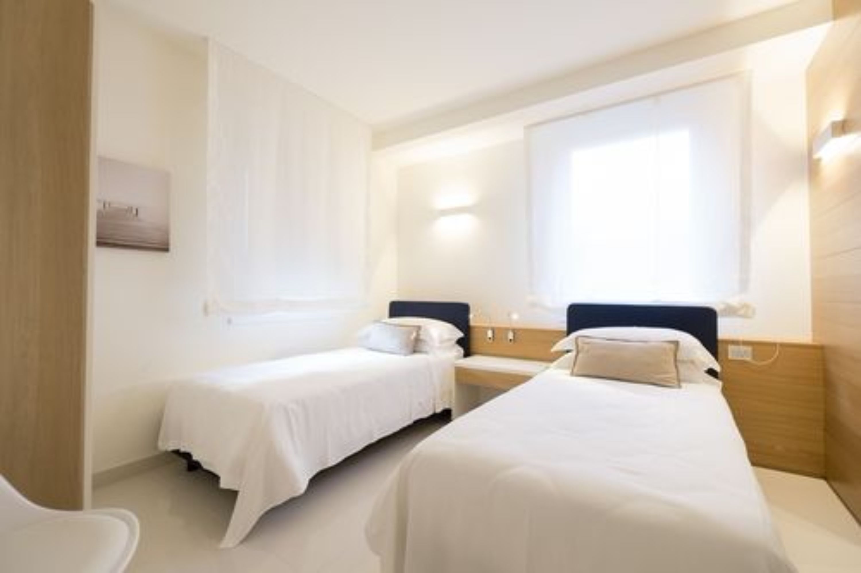 Una camera d'albergo con due letti singoli, una scrivania e una sedia.