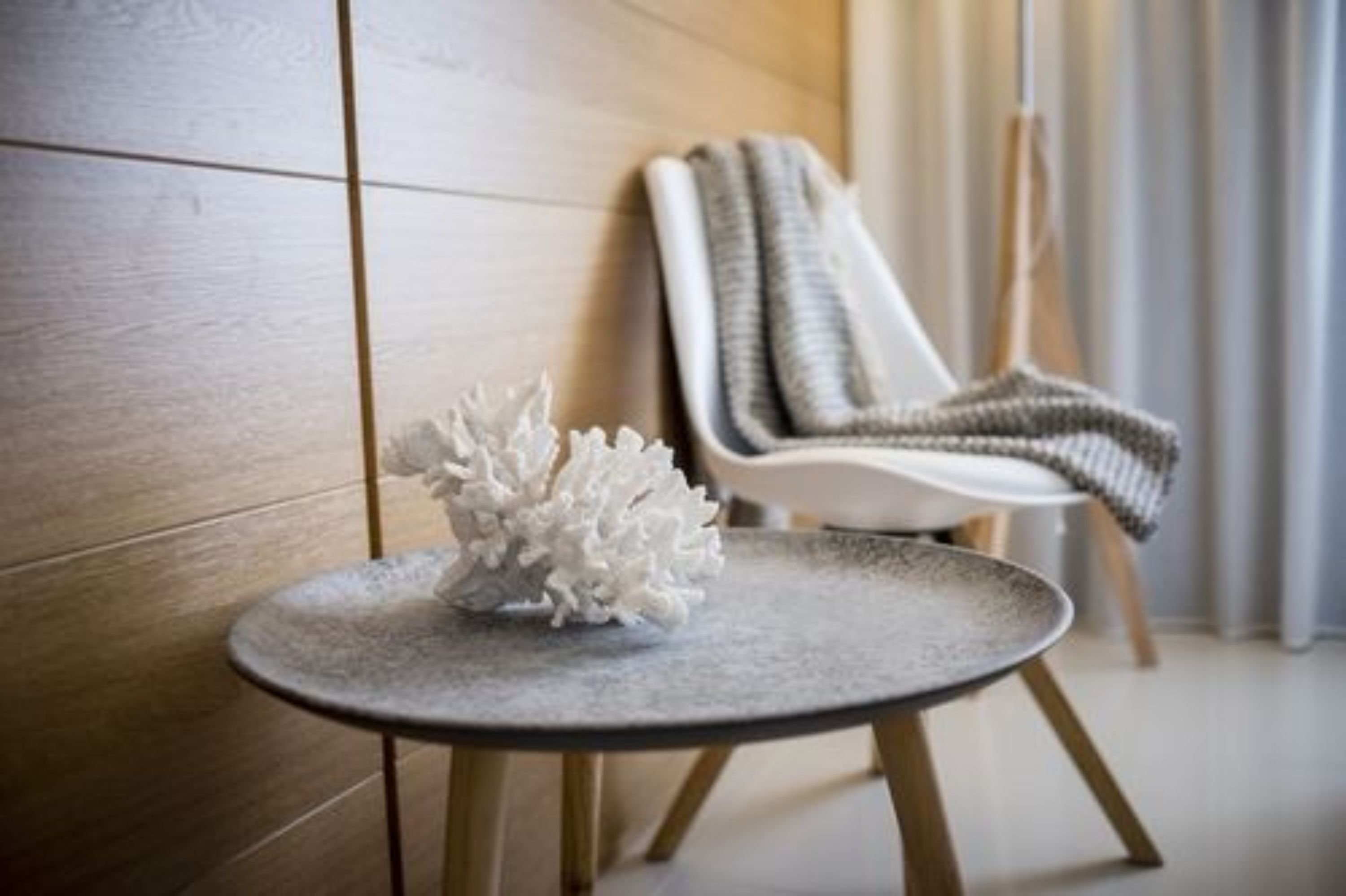 Una habitación moderna con una mesa redonda, una silla blanca y una pared con textura.