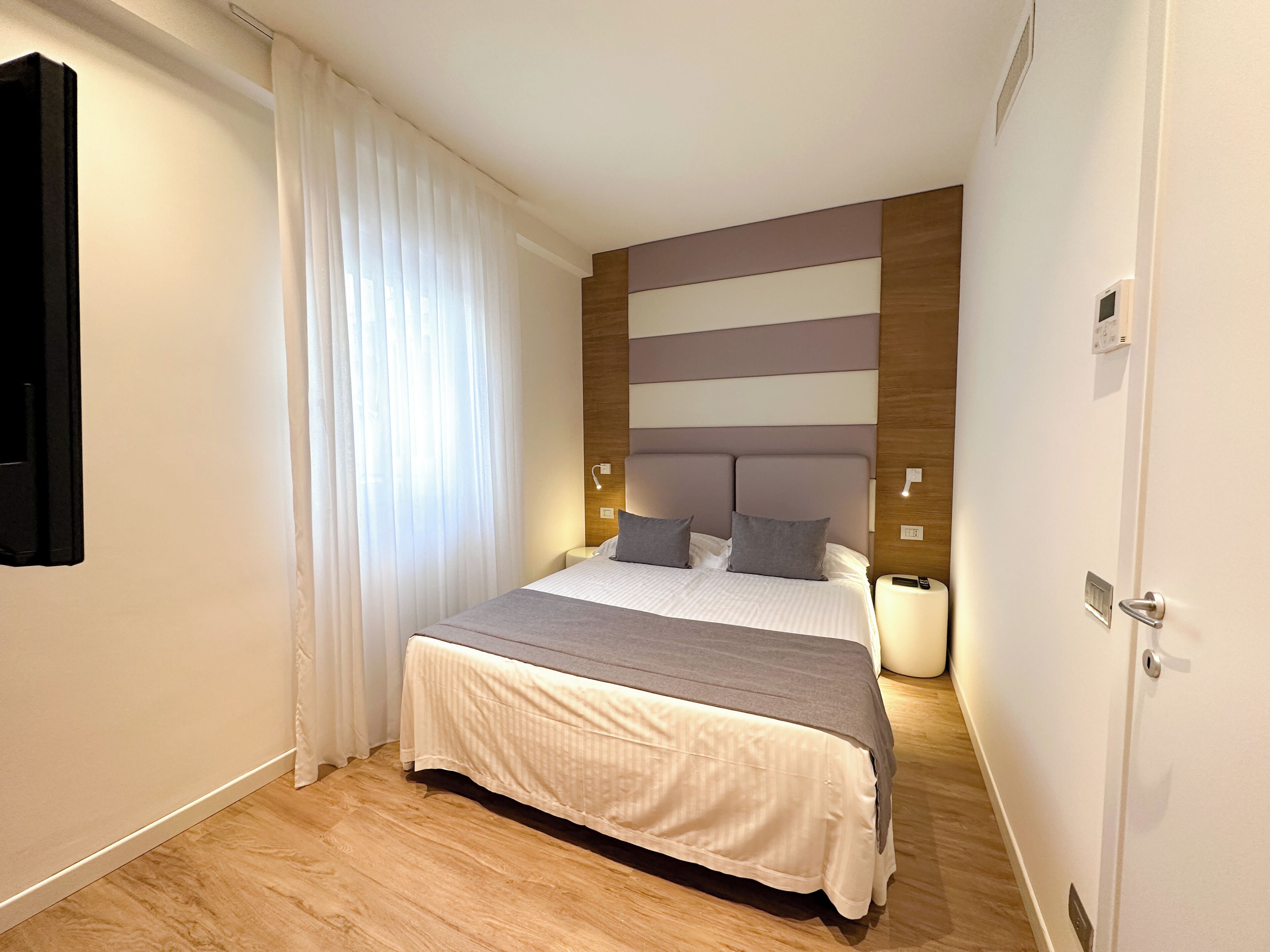 Ein modernes Schlafzimmer mit Bett, Vorhängen, einem Nachttisch und einem Beistelltisch.
