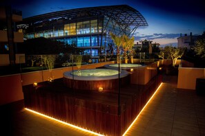 A rooftop pool area with hot tubs and a modern building in the background. - Metropol Ceccarini Suite - Luxury apartments (Riccione)