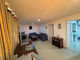 Una sala de estar con sofá, mesa de centro, televisor y comedor con mesa y sillas.