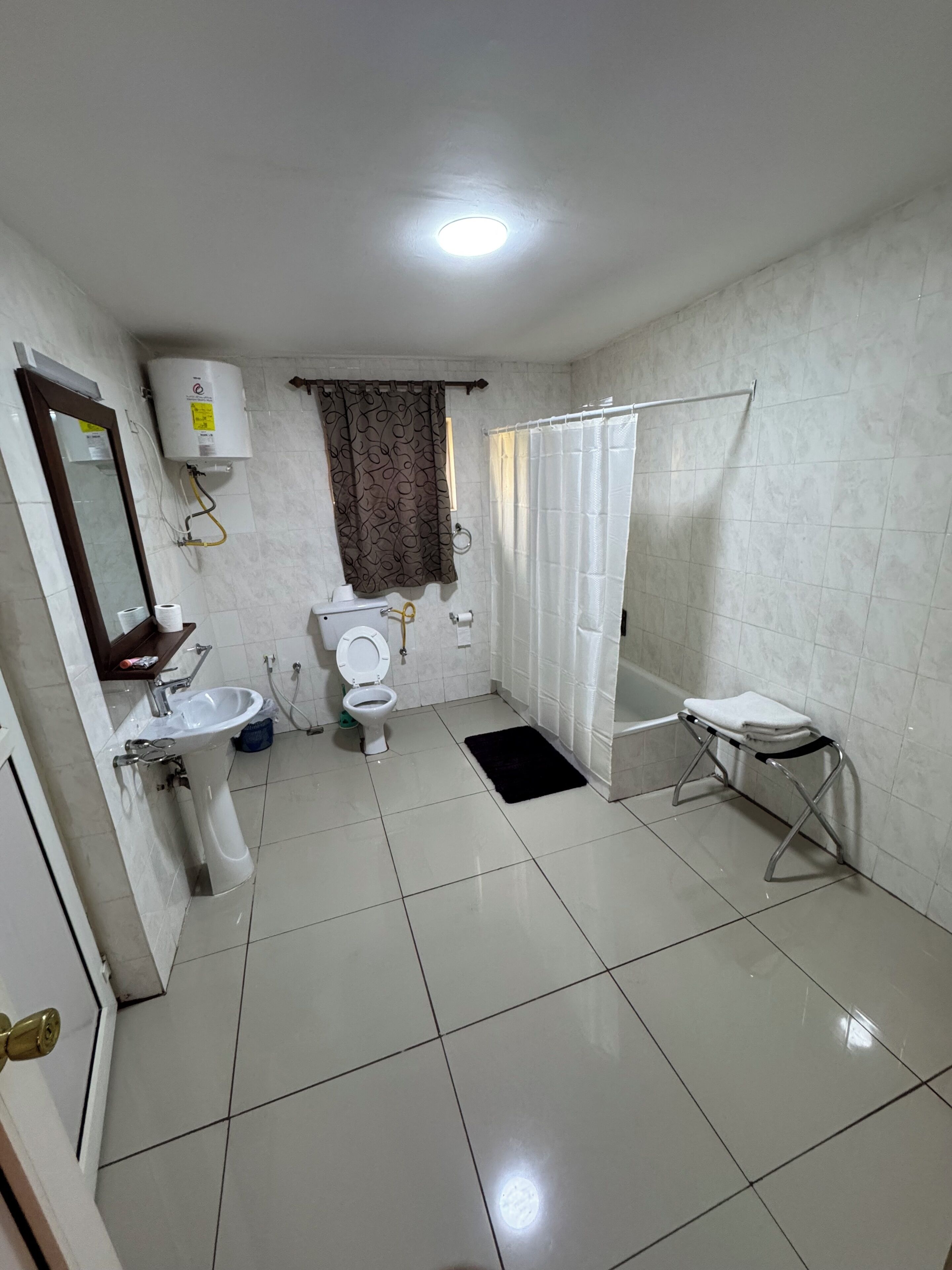 A bathroom with a toilet, sink, shower, and a towel rack.