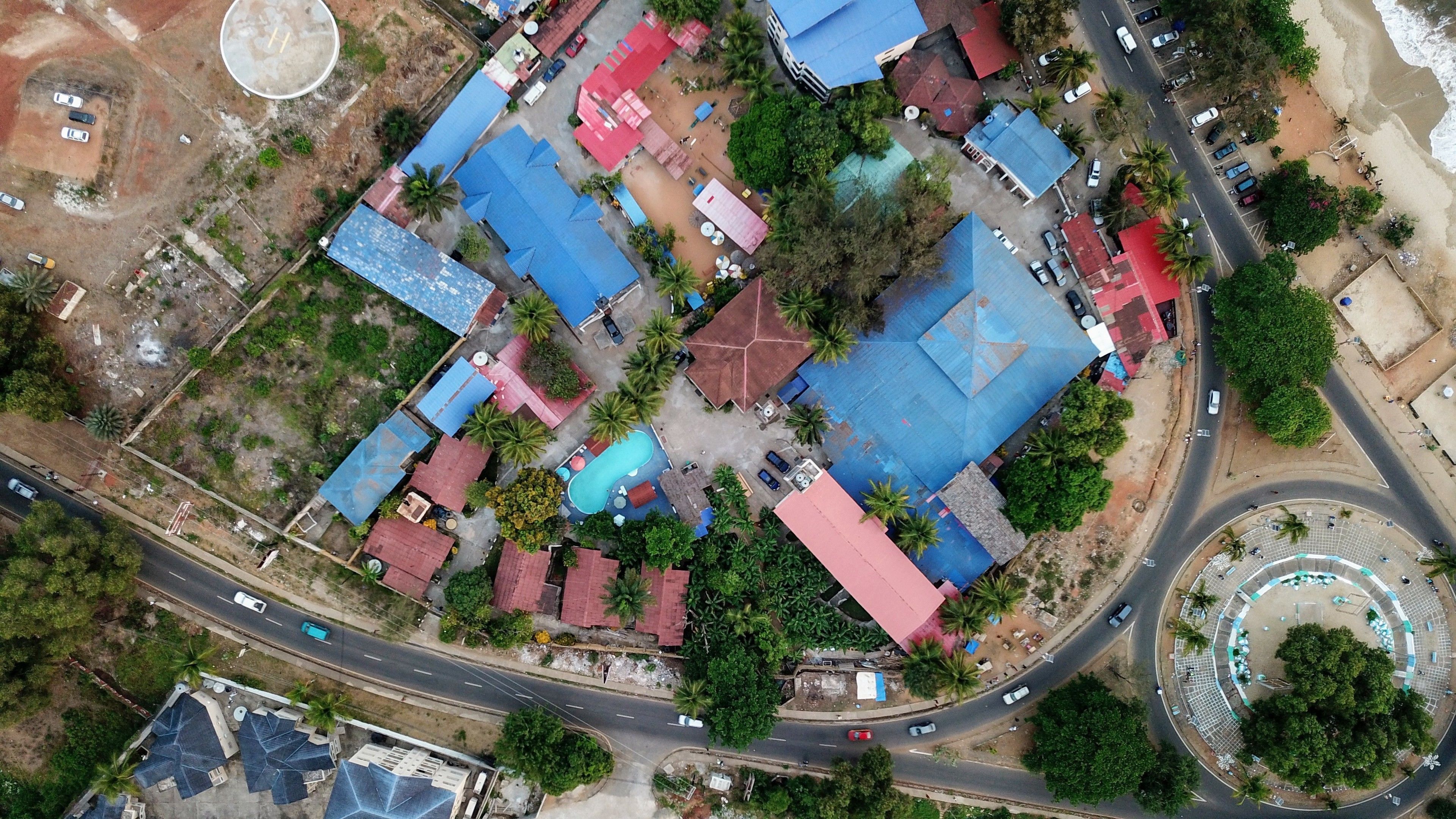 An aerial view of a residential area with multiple houses, a swimming pool, and a roundabout.